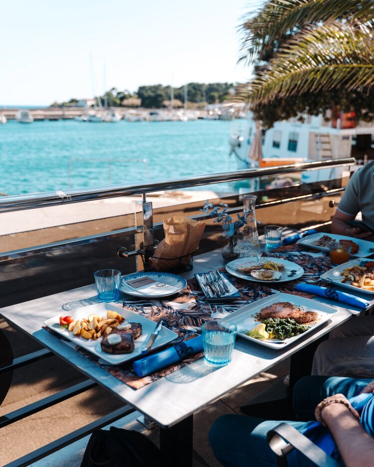 Gäste genießen traditionelle Gerichte aus Krk im Restaurant Marina Blue mit Blick auf die Adria in der Stadt Krk
